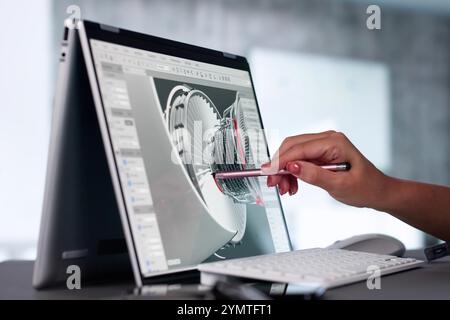 Ingénieur développant des pièces mécaniques à l'aide d'un logiciel de CAO 3D sur ordinateur portable au bureau de l'usine Banque D'Images