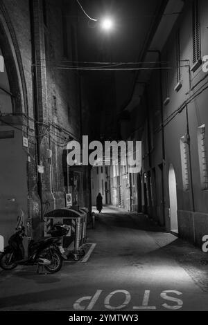 Vieilles maisons dans une rue étroite la nuit, avec panneau d'arrêt sur le plancher à Bologne, Italie 05.01.2024 Banque D'Images