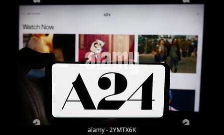 Dans cette illustration photo, une personne tient un téléphone portable avec le logo de la société de divertissement américaine A24 films LLC devant la page Web de l'entreprise. Banque D'Images