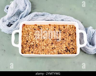 Gâteau granola de porridge d'avoine dans une plaque de cuisson blanche sur vert Banque D'Images