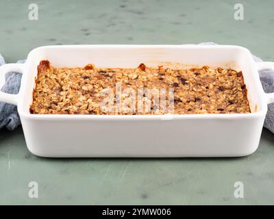 Gâteau granola de porridge d'avoine dans une plaque de cuisson blanche sur vert Banque D'Images