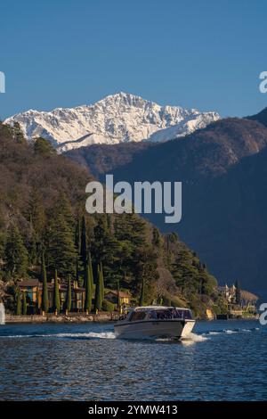 Bateau naviguant dans le lac de Côme, avec Villa la Cassinella à Ossuccio, beau village sur le lac de Côme en arrière-plan. Lombardie, Italie. 11.01.2024 Banque D'Images