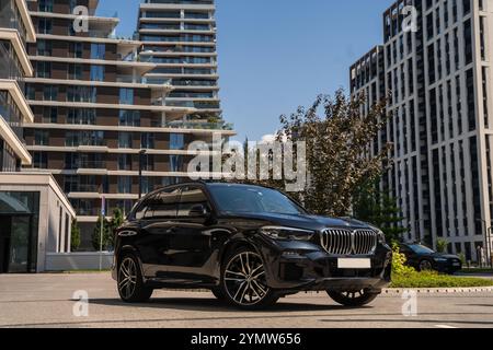 Black BMW X5 M, SUV garé dans la ville en face des immeubles résidentiels complexes de luxe à Belgrade, Serbie 04.07.2024 Banque D'Images