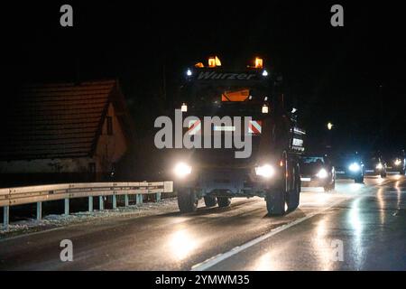 Erding, Bavière, Allemagne - 22 novembre 2024 : un véhicule de service hivernal répand le sel sur une route hivernale la nuit pour assurer la sécurité routière par temps de gel *** Ein Winterdienstfahrzeug streut in der Nacht Salz auf eine winterliche Straße, um die Verkehrssicherheit BEI frostigen Temperaturen zu gewährleisten Banque D'Images