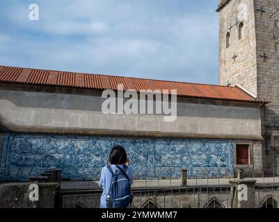 Panneau azulejo dans la cathédrale de Porto avec une fille touristique photographiant Banque D'Images