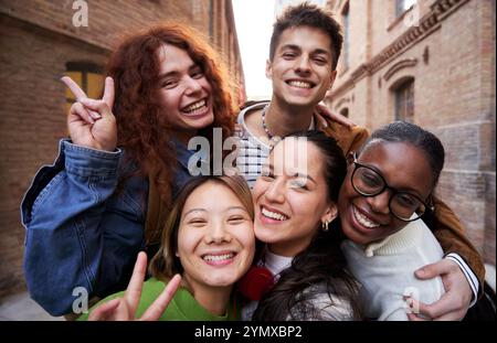Groupe joyeux d'amis étudiants multiethniques prenant un selfie ensemble à l'extérieur à l'université. Banque D'Images
