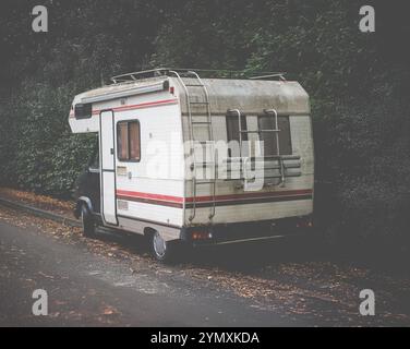 Un vieux camping-car grungy (ou véhicule récréatif ou camping-car) garé près D'Une route Banque D'Images