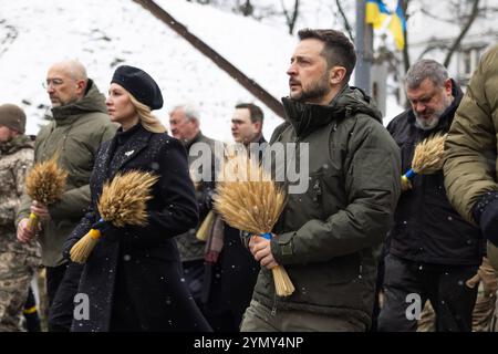 Kiev, Ukraine. 23 novembre 2024. La première dame ukrainienne Olena Zelenska, à gauche, et le président Volodymyr Zelenskyy, à droite, observent un moment de silence avant de placer des ciseaux de blé sur la statue amère mémoire de l’enfance honorant les victimes de la famine d’Holodomor lors d’une soirée enneigée sur les collines de Pechersk, le 23 novembre 2024 à Kiev, en Ukraine. L'Ukraine a marqué l'anniversaire de la famine massive des Ukrainiens par Staline qui a tué 4 millions de personnes. Crédit : Présidence ukrainienne/Bureau de presse présidentiel ukrainien/Alamy Live News Banque D'Images