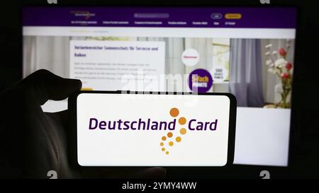 Stuttgart, Allemagne, 07-15-2024 : personne tenant un téléphone portable avec le logo de la société allemande de fidélisation de la clientèle DeutschlandCard GmbH devant le webpag d'affaires Banque D'Images