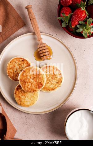 Crêpes au fromage cottage avec sauce blanche et fraises, sur une table beige, vue de dessus, focus sélectif, pas de gens Banque D'Images