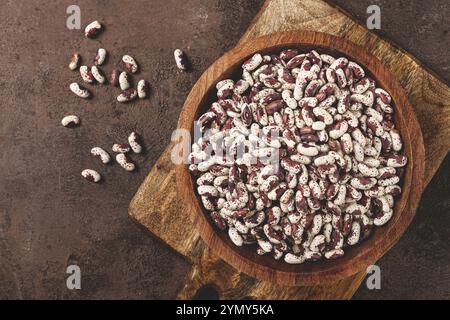 Haricots panachés, rouges avec des taches blanches, crus dans un bol en bois, vue de dessus, pas de gens Banque D'Images