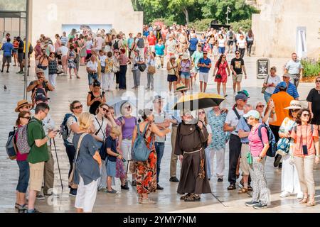 Valletta Malte, Republic Street, guide touristique à pied en groupe, hommes femmes couples familles, moine franciscain moine dirigeant, portant une robe brune, tenant un parapluie, s. Banque D'Images