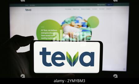 Stuttgart, Allemagne, 05-23-2024 : personne tenant un téléphone portable avec le logo de la société israélienne Teva Pharmaceutical Industries Ltd. Devant la page Web de l'entreprise Banque D'Images