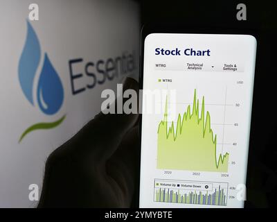 Stuttgart, Allemagne, 07-06-2024 : personne tenant un téléphone portable avec le site Web de la société américaine Essential Utilities Inc devant le logo. Concentrez-vous sur Banque D'Images