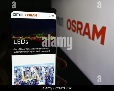 Stuttgart, Allemagne, 05-31-2024, personne tenant un téléphone portable avec la page web de la société autrichienne d'électronique AMS Osram AG devant le logo de l'entreprise. Concentrez-vous sur Banque D'Images