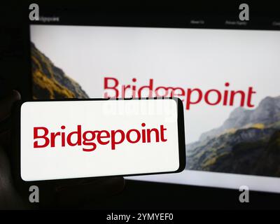 Stuttgart, Allemagne, 03-16-03 2024 : personne tenant un smartphone avec le logo de la société d'investissement britannique Bridgepoint Group plc devant le site Web. Concentrez-vous sur Banque D'Images