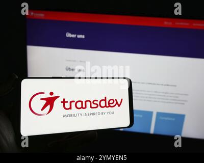 Stuttgart, Allemagne, 03-05-2024 : personne tenant un téléphone portable avec le logo de la société allemande de transport public Transdev GmbH devant la page web de l'entreprise. Banque D'Images