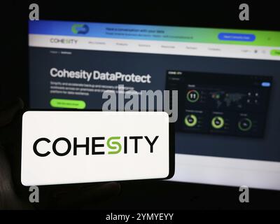 Stuttgart, Allemagne, 05-21-05 2024 : personne tenant un téléphone portable avec le logo de la société américaine de gestion de données Cohesity Inc devant la page Web de l'entreprise. Banque D'Images