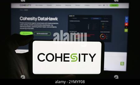 Stuttgart, Allemagne, 05-21-05 2024 : personne tenant un téléphone portable avec le logo de la société américaine de gestion de données Cohesity Inc en face de la page Web de l'entreprise. Concentrez-vous sur Banque D'Images