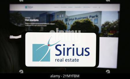 Stuttgart, Allemagne, 04-08-2024 : personne tenant un téléphone portable avec le logo de la société de propriété commerciale Sirius Real Estate Limited en face de la page Web. Focu Banque D'Images