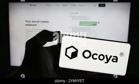 Stuttgart, Allemagne, 03-13-2024 : personne tenant un téléphone portable avec le logo de la société lituanienne d'intelligence artificielle Ocoya en face de la page Web de l'entreprise. F Banque D'Images