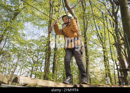 Portrait d'un petit garçon mignon marcher sur un pont de corde dans un parc de corde d'aventure Banque D'Images