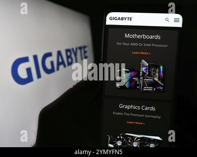 Stuttgart, Allemagne, 02-24-2024 : personne tenant le téléphone portable avec la page Web de la société taïwanaise de matériel informatique Gigabyte Technology avec le logo. Concentrez-vous sur c Banque D'Images