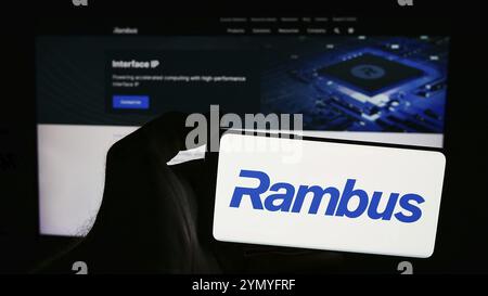Stuttgart, Allemagne, 06-11-2024 : personne tenant un smartphone avec le logo de la société américaine de semi-conducteurs Rambus Inc en face du site. Concentrez-vous sur le téléphone Banque D'Images