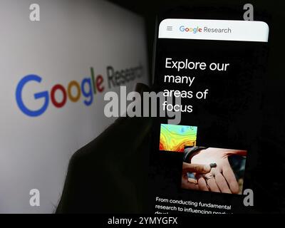 Stuttgart, Allemagne, 04-02-2024 : personne tenant un téléphone portable avec la page Web de la société de technologie américaine Google Research devant le logo de l'entreprise. Focus sur le cen Banque D'Images