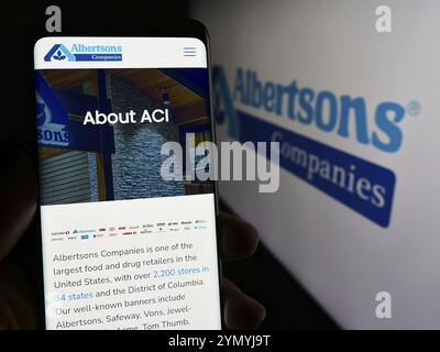Stuttgart, Allemagne, 03-13-2024 : personne tenant un téléphone portable avec la page Web de la société américaine de vente au détail d'épicerie Albertsons Companies Inc. avec le logo. Concentrez-vous sur c Banque D'Images