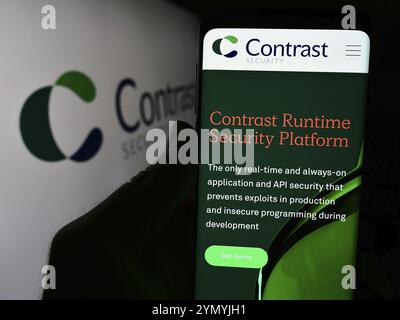 Stuttgart, Allemagne, 05-14-2024 : personne tenant un téléphone portable avec la page Web de la société américaine de logiciels Contrast Security Inc devant le logo de l'entreprise. Focus o o Banque D'Images