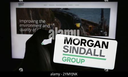 Stuttgart, Allemagne, 03-25-2024, personne tenant un smartphone avec le logo de l'entreprise de construction britannique Morgan Sindall Group plc devant le site. Focu Banque D'Images