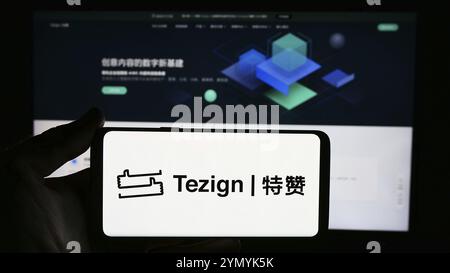 Stuttgart, Allemagne, 05-15-2024 : personne tenant un téléphone portable avec le logo de la société chinoise d'analyse de contenu Tezign devant la page Web de l'entreprise. Concentrez-vous sur Banque D'Images