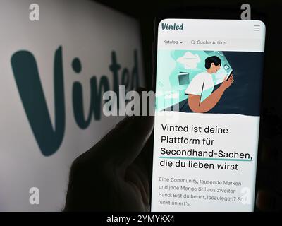 Stuttgart, Allemagne, 03-17-03 2024 : personne tenant un smartphone avec la page web de la société de marché d'occasion en ligne Vinted devant le logo. Concentrez-vous sur cent Banque D'Images