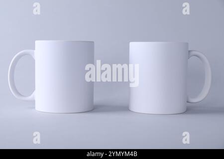 Deux tasses blanches vierges sur fond clair. Maquette pour le design Banque D'Images