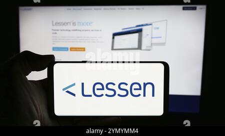 Stuttgart, Allemagne, 05-14-2024 : personne tenant un téléphone portable avec le logo de la société américaine de marché de services immobiliers Lessen Inc devant le webpag d'affaires Banque D'Images