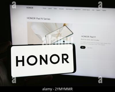 Stuttgart, Allemagne, 03-15-2024 : personne tenant un smartphone avec le logo de la société chinoise de smartphones Honor Device Co. Ltd en face du site Web. Concentrez-vous sur Banque D'Images