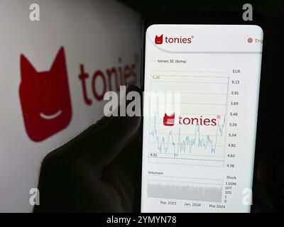 Stuttgart, Allemagne, 05-22-2024 : personne tenant un téléphone portable avec le site web de la société allemande de vente au détail de jouets Tonies se (Toniebox) devant le logo. Focus sur le cen Banque D'Images