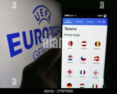 Stuttgart, Allemagne, 05-16-05 2024 : personne tenant un smartphone avec la page web du championnat d'Europe de football UEFA Euro 2024 devant le logo. Focus sur le cen Banque D'Images