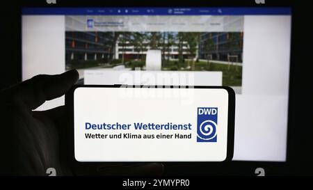 Stuttgart, Allemagne, 06-06-2024 : personne tenant un téléphone portable avec le logo du service météorologique allemand Deutscher Wetterdienst (DWD) devant la page web. Banque D'Images
