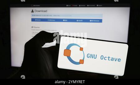 Stuttgart, Allemagne, 03-13-2024 : personne tenant un téléphone portable avec le logo du langage de programmation scientifique GNU Octave devant la page web. Concentrez-vous sur pho Banque D'Images