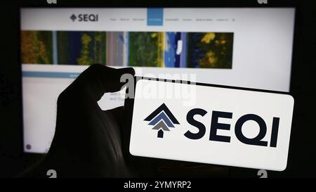 Stuttgart, Allemagne, 04-07-2024 : personne tenant un smartphone avec le logo de Sequoia Economic infrastructure Income Fund Limited (SEQI) devant le site. Banque D'Images