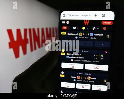 Stuttgart, Allemagne, 06-06-2024 : personne tenant un smartphone avec la page web de la société française de Paris sportifs Winamax sa devant le logo de l'entreprise. Concentrez-vous sur Banque D'Images