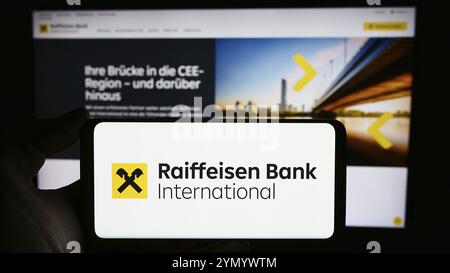 Stuttgart, Allemagne, 03-16-03 2024 : personne tenant un téléphone portable avec le logo de la société autrichienne Raiffeisen Bank International AG (RBI) devant la page web. FOC Banque D'Images