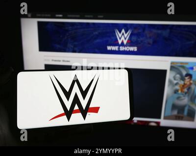 Stuttgart, Allemagne, 03-07-2024 : personne tenant un téléphone portable avec le logo de la société de promotion World Wrestling Entertainment (WWE) devant la page web. F Banque D'Images