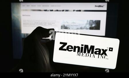 Stuttgart, Allemagne, 03-05-2024 : personne tenant un téléphone portable avec le logo de la société américaine de jeux vidéo ZeniMax Media Inc en face de la page Web de l'entreprise. Concentrez-vous sur Banque D'Images