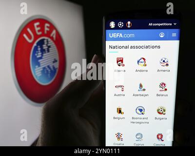 Stuttgart, Allemagne, 06-25-2024, personne tenant un téléphone portable avec le site web de l'Union des associations européennes de football (UEFA) devant le logo. Focus sur le cen Banque D'Images