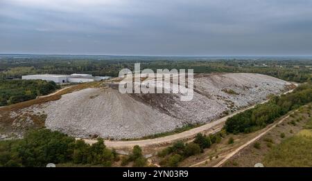 Une perspective aérienne d’un grand site d’enfouissement situé en zone rurale, bordé de forêts denses et de champs agricoles. Le paysage contrasté h Banque D'Images