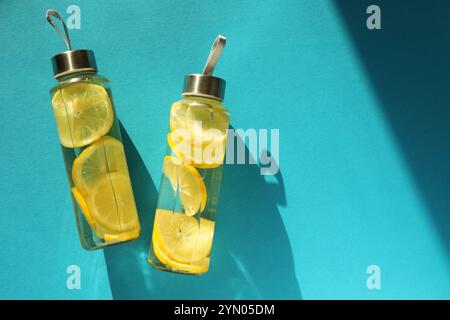 Eau de citron dans des bouteilles sur fond bleu, vue de dessus. Espace pour le texte Banque D'Images