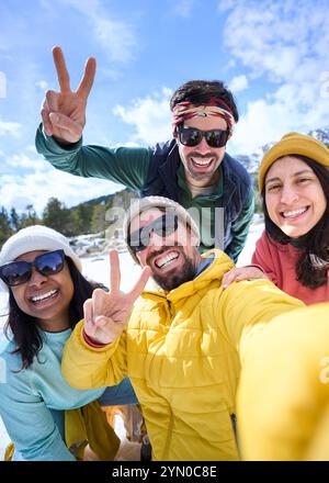 Selfie de l'homme caucasien et femme latina regardant souriant à la caméra sur la montagne de neige en vacances. Banque D'Images